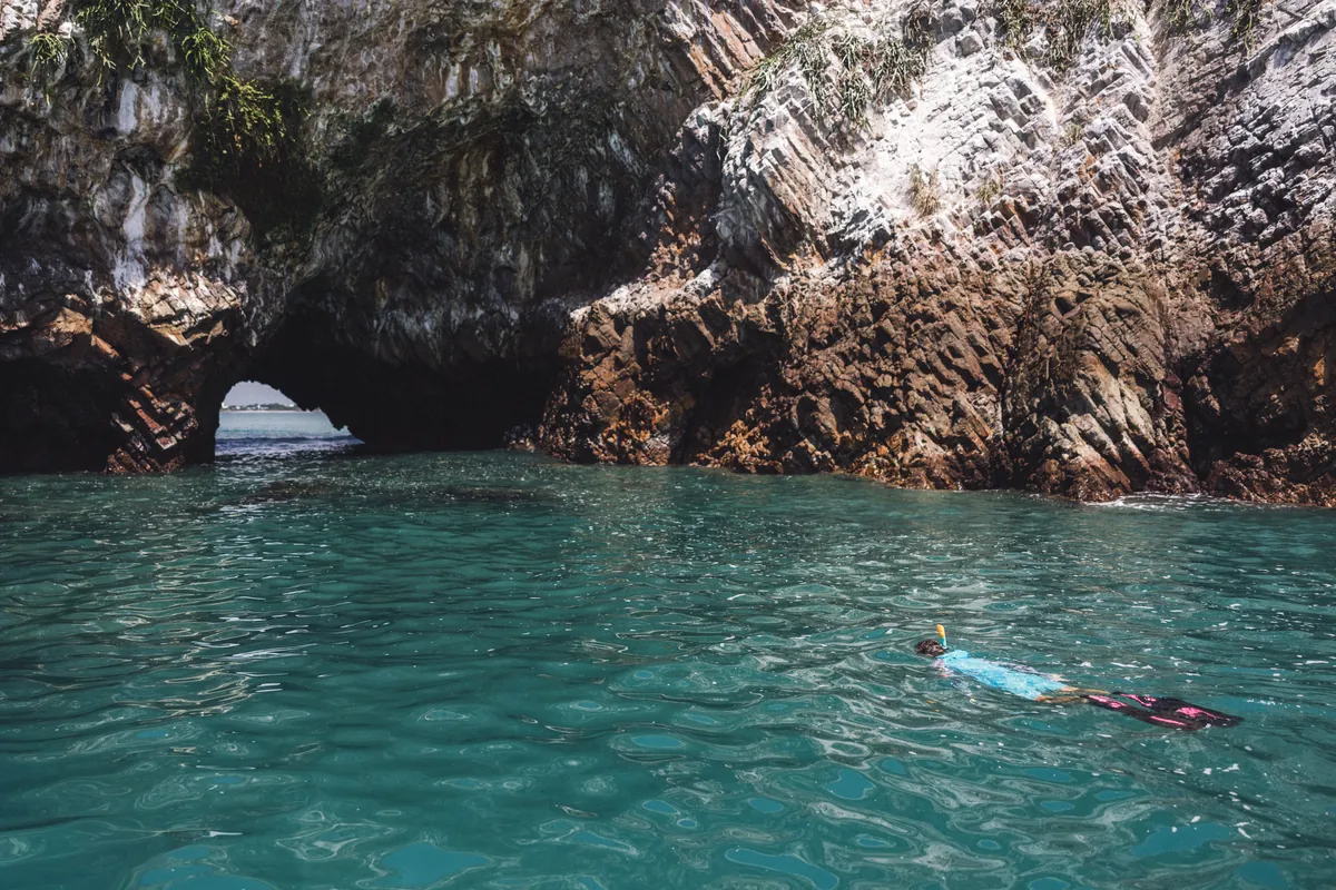 Natural sea arch rock formation and crystal turquoise water at Isla Farallón